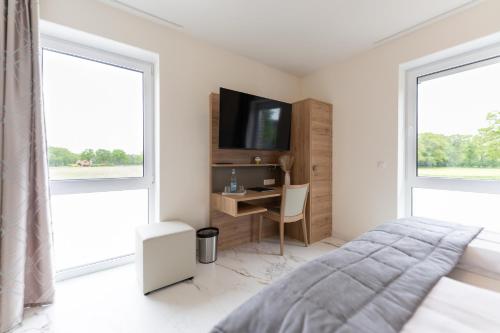 a bedroom with a bed and a desk and two windows at Hotel & Restaurant Sparta in Oldenburg