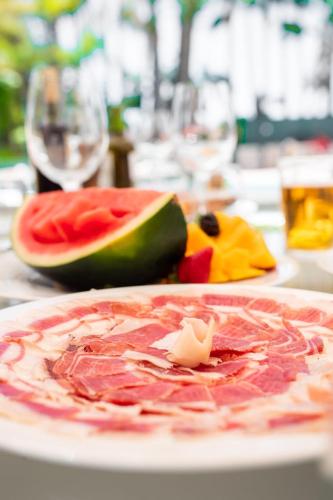 a plate of food on a table with watermelon at Guadalpin Suites in Marbella
