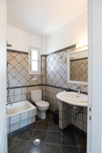 a bathroom with a toilet and a sink and a tub at Sea Lilies Suites in Plaka