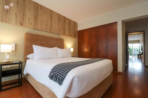 Spectacular 1BR in Miraflores في ليما: غرفة نوم بسرير ابيض كبير وجدران خشبية