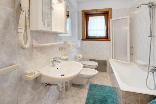 un bagno bianco con lavandino e WC di Bait dal Cucù App Plascianet a Livigno