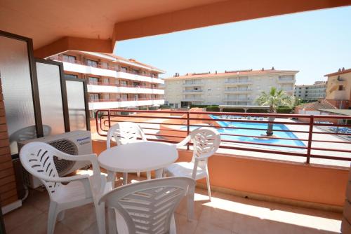 balcón con mesa, sillas y piscina en Apartamentos familiares Sa Gavina Gaudí, en L'Estartit