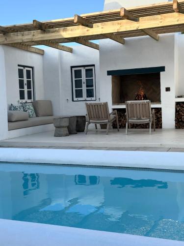 a swimming pool with two chairs and a fireplace at Seagulls Nest in Struisbaai