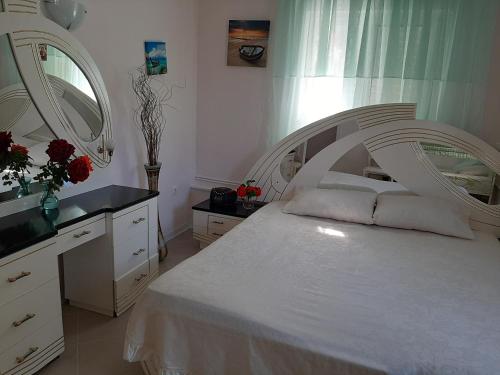 Schlafzimmer mit einem weißen Bett und einem Spiegel in der Unterkunft Cozy flat in Nea Makri in Nea Makri