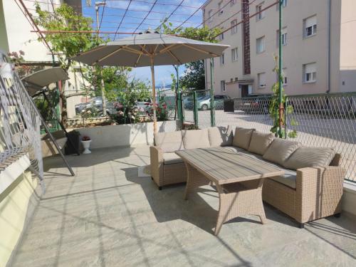 een patio met een bank, een tafel en een parasol bij Apartman Noel Knin in Knin