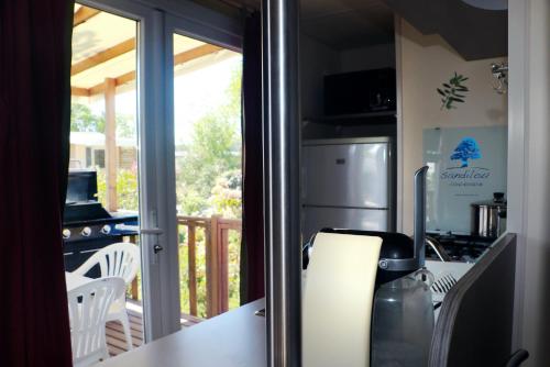 a kitchen with a refrigerator and a table with a stove at Mobilhome Côté mer - 3 Chambres - Climatisé - TV in Sigean