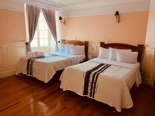米內拉德蒙特的住宿－Hotel Real Del Monte，酒店客房设有两张床和窗户。