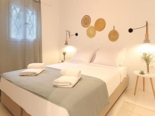 Un dormitorio blanco con una cama grande con toallas. en La Vista TINOS, en Agios Ioannis