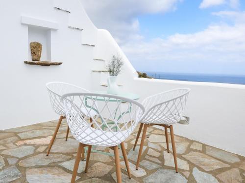 a table and chairs on a balcony overlooking the ocean at La Vista TINOS in Agios Ioannis Tinos