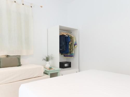 a white bedroom with a bed and a closet at La Vista TINOS in Agios Ioannis Tinos