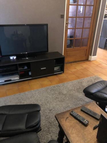 een woonkamer met een flatscreen-tv en stoelen bij Couleur Framboise in Longwy