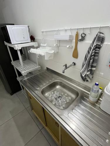 a kitchen with a sink in a kitchen with a microwave at Apt Central Caraguá in Caraguatatuba