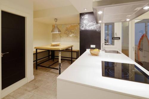 eine Küche mit einer weißen Theke und einem Tisch in der Unterkunft 186A Magnífico Apto en La Arena in Gijón