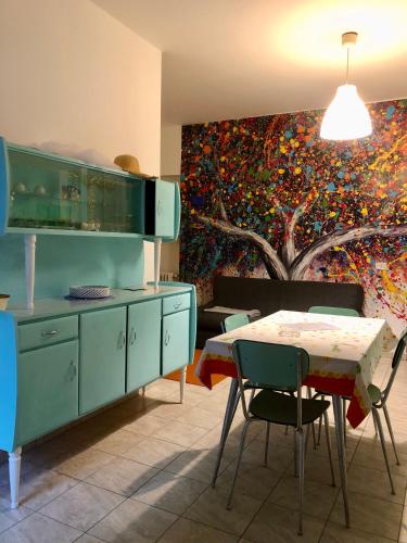 Candelo的住宿－L’Albero Colorato，厨房配有桌子,墙上挂有绘画作品