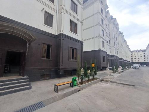 uma rua vazia com edifícios e um banco na frente em Comfortable 3-roomed apartment Ozod Apartments em Samarkand