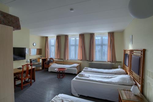 マリボにあるEbsens Hotelのベッド2台とリビングルームが備わるホテルルームです。