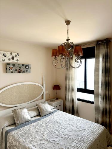 a bedroom with a bed with a chandelier and a window at Apartamento Lujo Calaceite in Torrox Costa