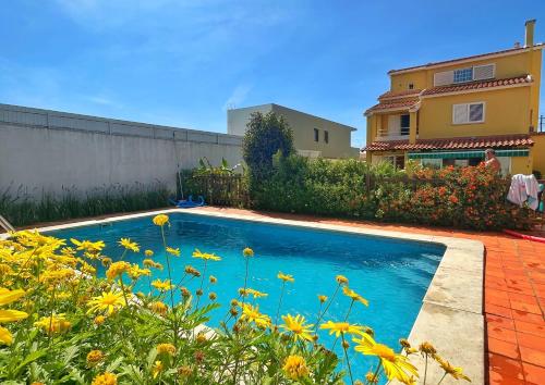 a swimming pool in front of a house with yellow flowers at Oceans house - Pool, Sauna, 26 Sleeps, 7m to beach in Carcavelos