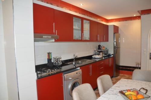 a kitchen with red cabinets and a sink and a table at la baie de Tanger in Tangier