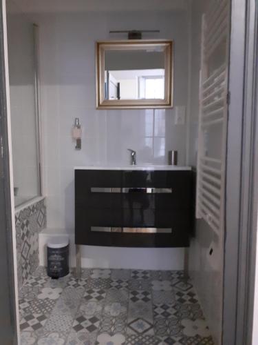 uma casa de banho com um lavatório preto e um espelho em Le studio de la Clarté em Périgueux