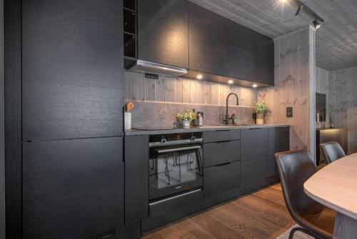 a kitchen with black cabinets and a table at Exclusive Suite in the Sunnmøre Alps, Near Geiranger & Hjørundfjord in Stranda