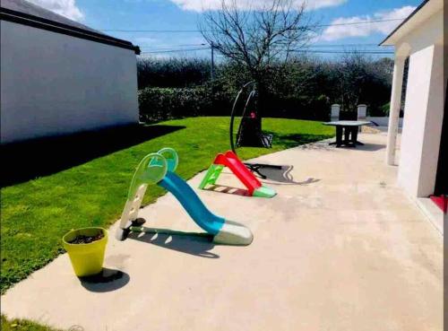 une cour arrière avec deux jeux pour enfants sur l'herbe dans l'établissement Maison 3 chambres au calme, à Pluvigner