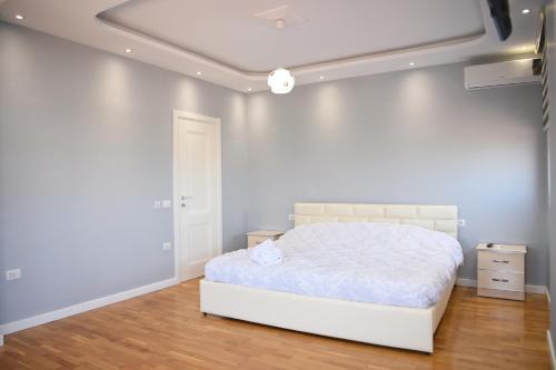 um quarto com uma cama branca e um tecto branco em Durres Luxury Beach Apartment em Durrës