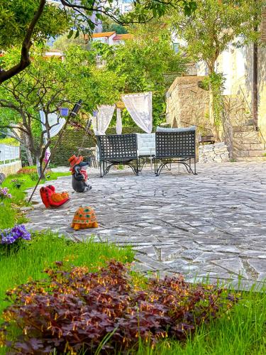 two benches sitting on a stone patio with flowers at Serenita Stone House in Becici