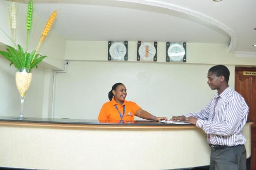 a man and a woman shaking hands behind a counter at Decasa Hotel in Nairobi