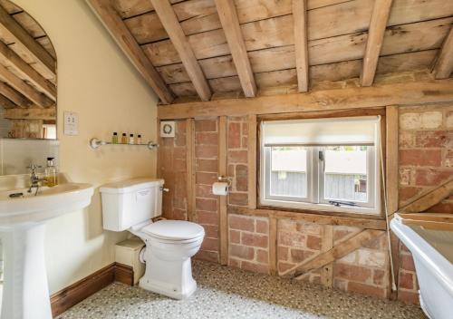 a bathroom with a toilet and a sink and a tub at Sewell Barn Sutton in Sutton