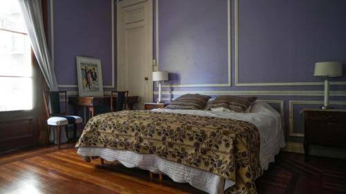a bedroom with a large bed with purple walls at Historical Tango House. Priv area 3 BR /7 guests. in Buenos Aires