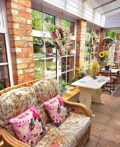 a living room with a couch and a table and windows at Canalside B and B in Yelvertoft