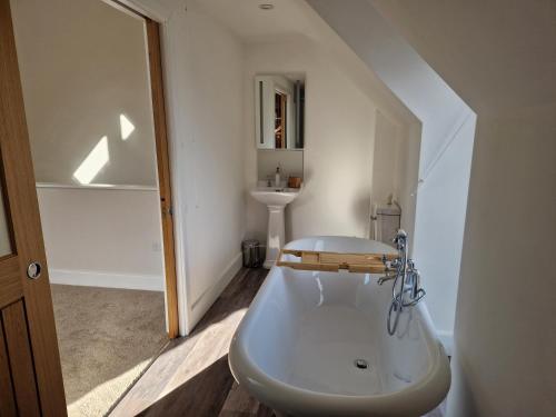 a white bathroom with a tub and a sink at The Old Pig Sty in Llanellen