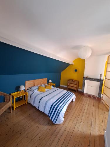 a bedroom with a bed and a blue wall at A deux pas d'la mer in Grandcamp-Maisy