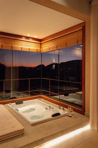 a bath tub in a room with a large window at Lofts Villa Gratiam in Tiradentes
