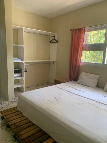 a bedroom with a white bed and a window at Hermosa casa en Cabarete, Villa Esperanza in Cabarete