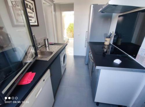 - une petite cuisine avec comptoirs noirs et évier dans l'établissement Maison Mathilde et Simone, à Andernos-les-Bains