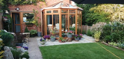 a greenhouse in a garden with potted plants at Park House in Leicester