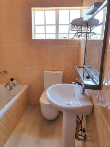 a bathroom with a sink and a toilet and a tub at Stream Box Lodge in Lilongwe