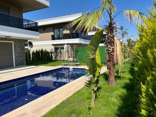 een huis met een zwembad en een palmboom bij Nirvana Belek Villas in Belek