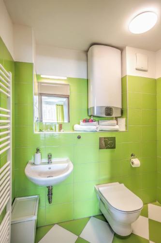 a green bathroom with a sink and a toilet at Elendris - Ubytování u kostela in Brno