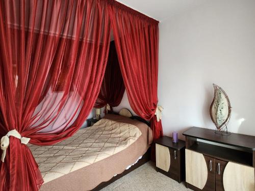 ピテシュティにあるApartament ULTRACENTRALのベッドルーム1室(赤いカーテン付きのベッド1台付)