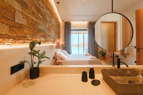 a bathroom with a sink and a mirror and a bedroom at Villa Mirabilis in Ios Chora