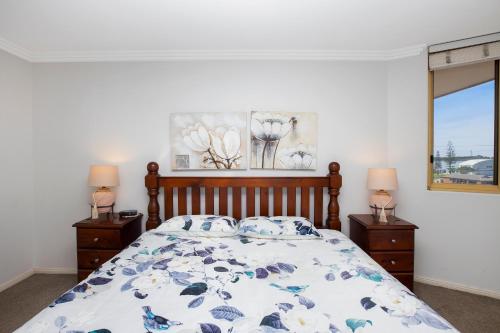 a bedroom with a bed and two night stands with lamps at Riviera 306 in Port Macquarie