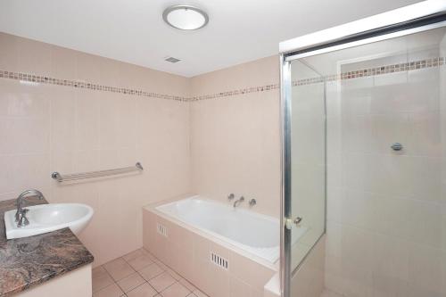 y baño con ducha, bañera y lavamanos. en Riviera 306 en Port Macquarie
