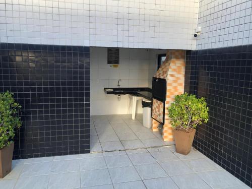 een badkamer met zwarte tegels en een wastafel in een gebouw bij Apartamento completo - Jatiúca - Perto de tudo in Maceió