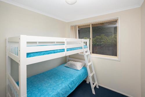 Ce lit superposé blanc se trouve dans un dortoir doté d'un matelas bleu. dans l'établissement Kelvin Grove 1, à Port Macquarie