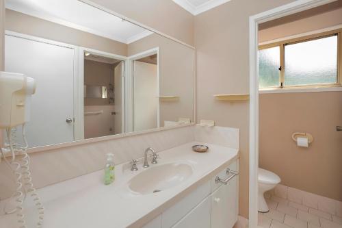La salle de bains blanche est pourvue d'un lavabo et d'un miroir. dans l'établissement Kelvin Grove 1, à Port Macquarie