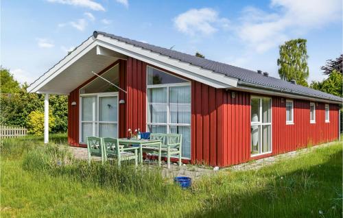 a red cottage with a table and chairs in the grass at Nice Home In Beder With Kitchen in Beder
