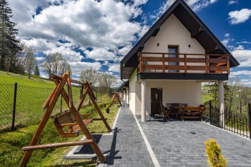 a small house with a porch and a playground at DOMKI NA WIERCHU in Biały Dunajec
